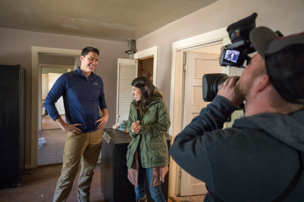 Ken and Anita Corsini are filmed by a cameraman inside a house for their HGTV series