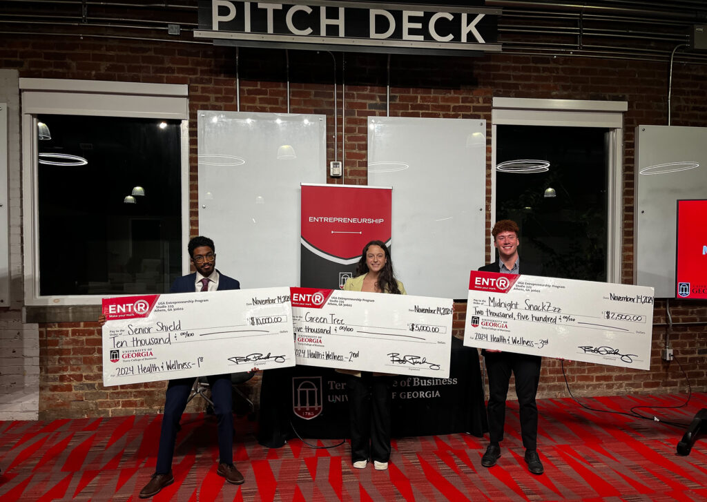 Kareem Elfoulie, Halle Greenbaum and Michael Hearnes stand in front of a sign that says pitch deck at Studio 225.