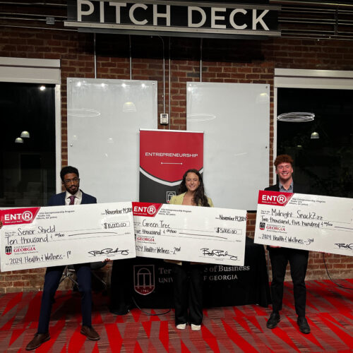 Kareem Elfoulie, Halle Greenbaum and Michael Hearnes stand in front of a sign that says pitch deck at Studio 225.