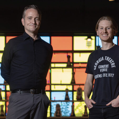 Two men posing in front of stained glass