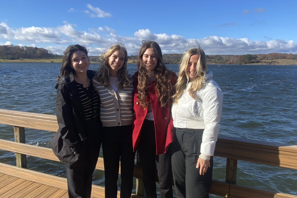 4 students pose for photo with lake in the background