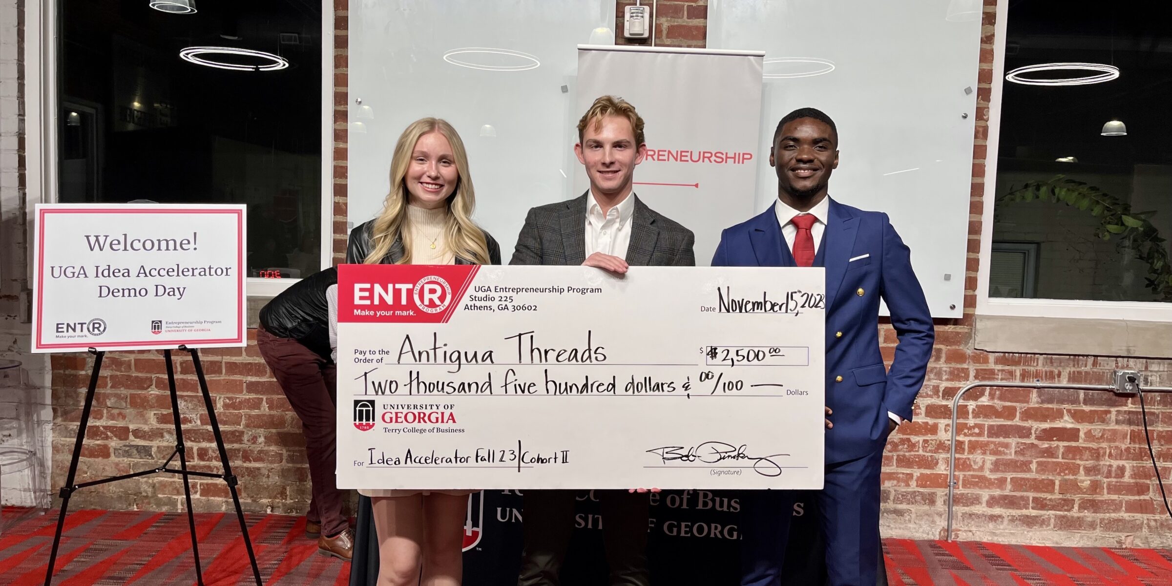 Kelsie Pearson, Moss Davis and Mbeng Juvis pose after pitching at the UGA Idea Acclerator. Davis, in the middle, holds large prize check.