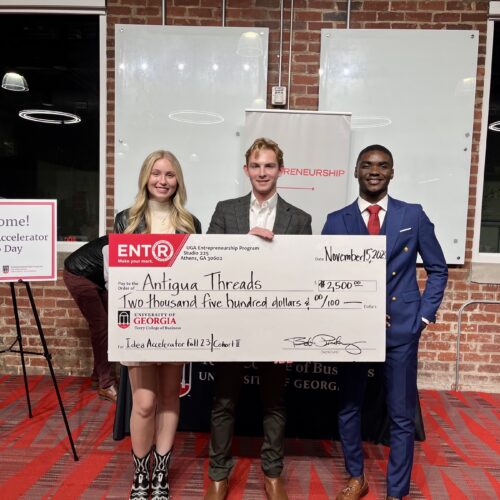 Kelsie Pearson, Moss Davis and Mbeng Juvis pose after pitching at the UGA Idea Acclerator. Davis, in the middle, holds large prize check.