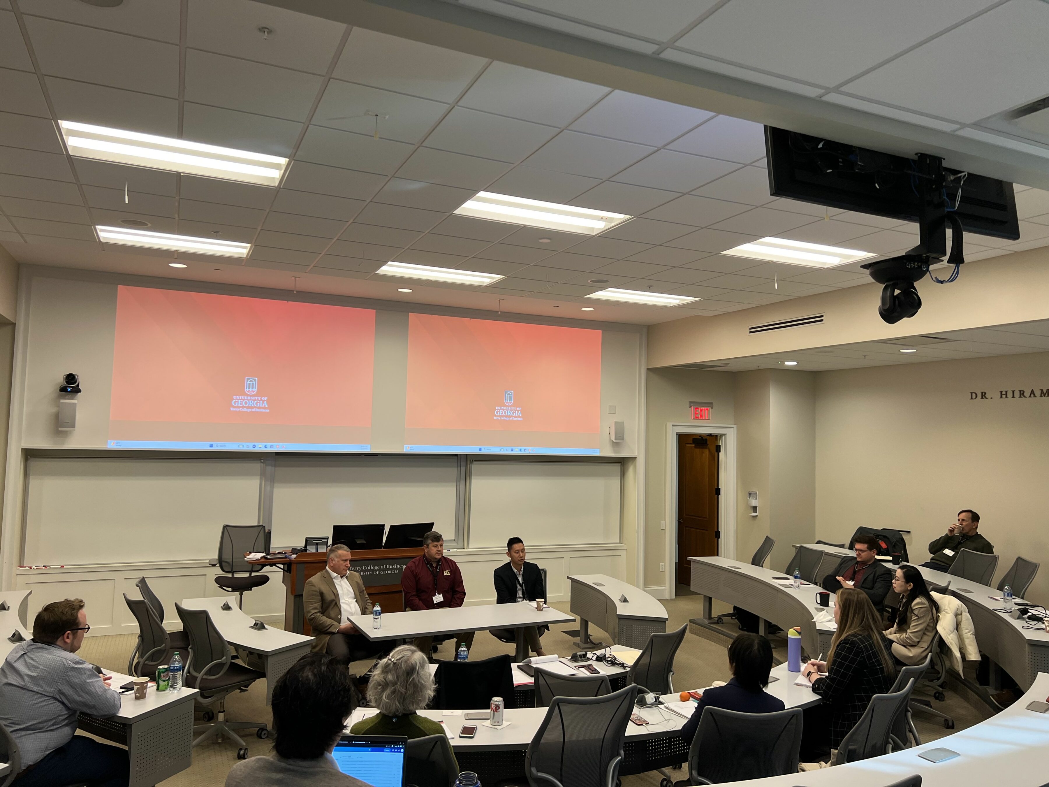 Participants in the Risk Management & Insurance Symposium listen to three speakers sitting in front of them in a BLC classroom.