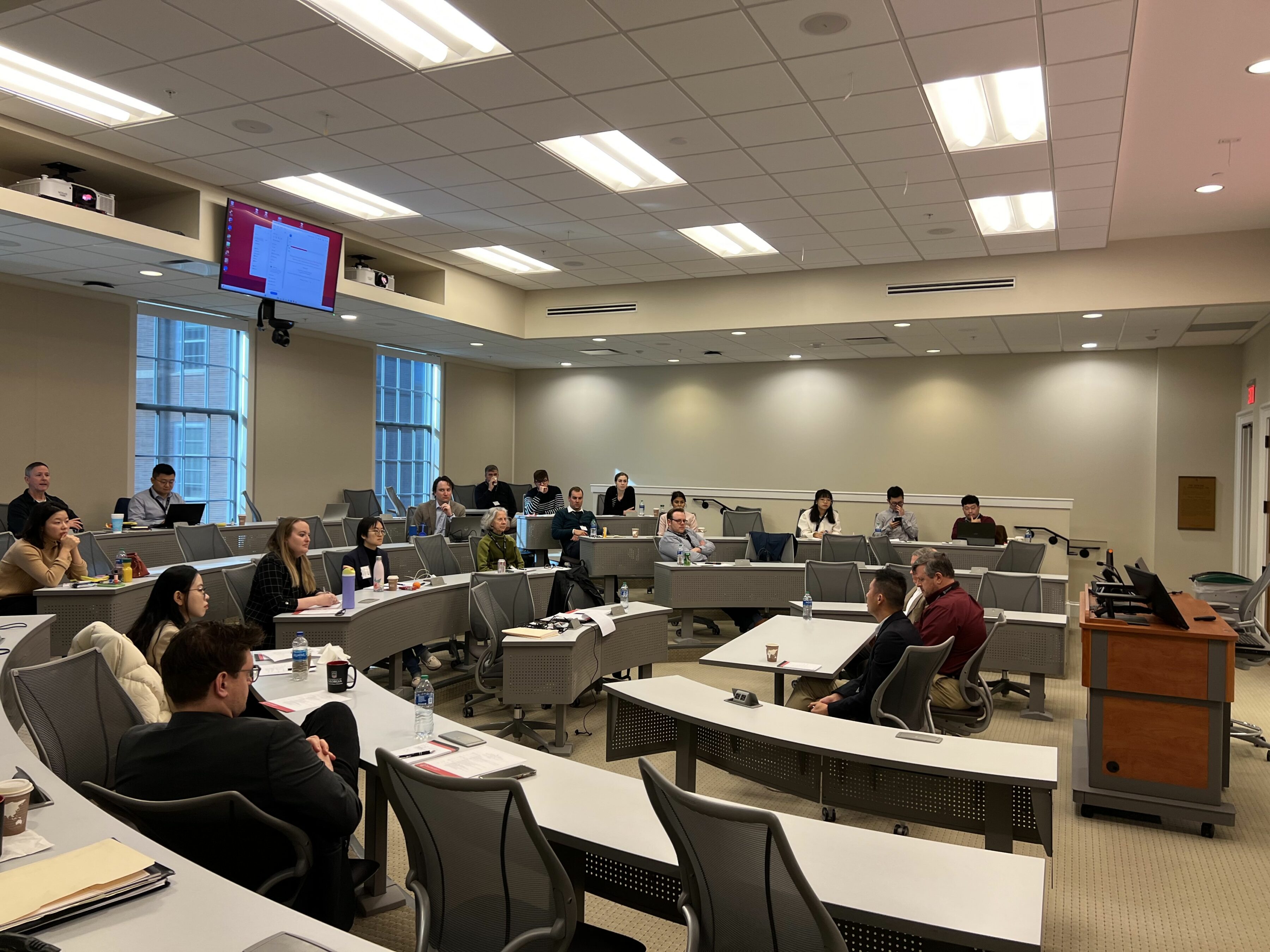 Participants in the Risk Management & Insurance Symposium listen to three speakers sitting in front of them in a BLC classroom.