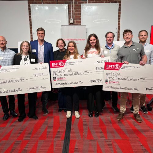 Winners of the 2024 Collegiate Great Brands pitch competition stand with their novelty prize checks with the contest's four judges behind them at Studio 225.