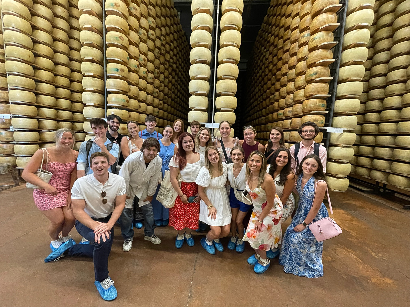 Terry students pose in front of aisles of aging Parmesan cheese at a factory outside of Milan Italy