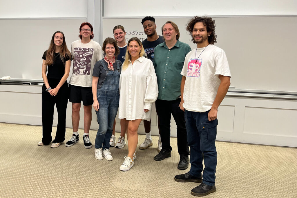 Julie Greenberg, center in white dress, stands with UGA Music Business Associate Director Lane Marie O'Kelley, Instructor Andrew Rieger and music business students in at Terry College classroom.