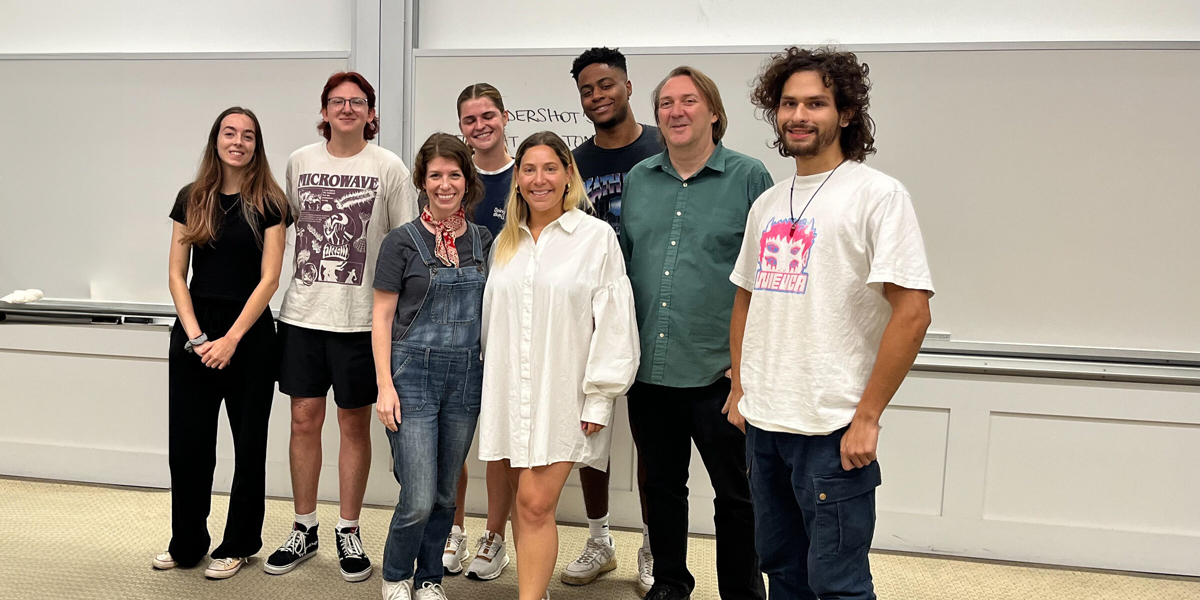 Julie Greenberg, center in white dress, stands with UGA Music Business Associate Director Lane Marie O'Kelley, Instructor Andrew Rieger and music business students in at Terry College classroom.