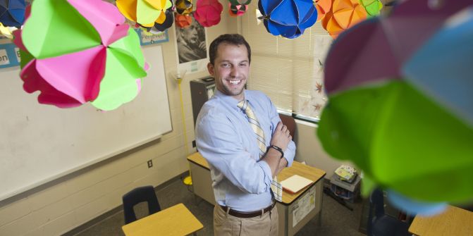 Zack Kroll poses for a photo in a classroom.