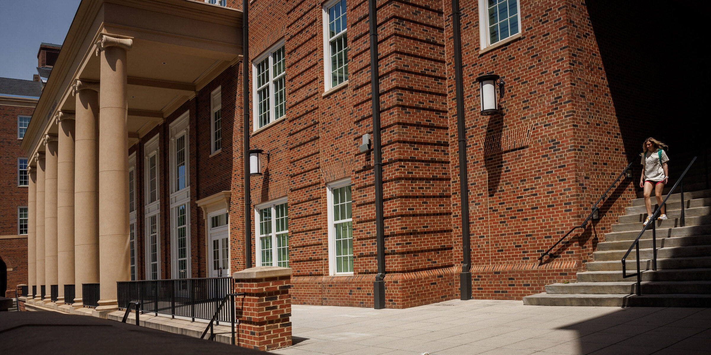 A female student walks down the stairs outside the Business Learning Community.