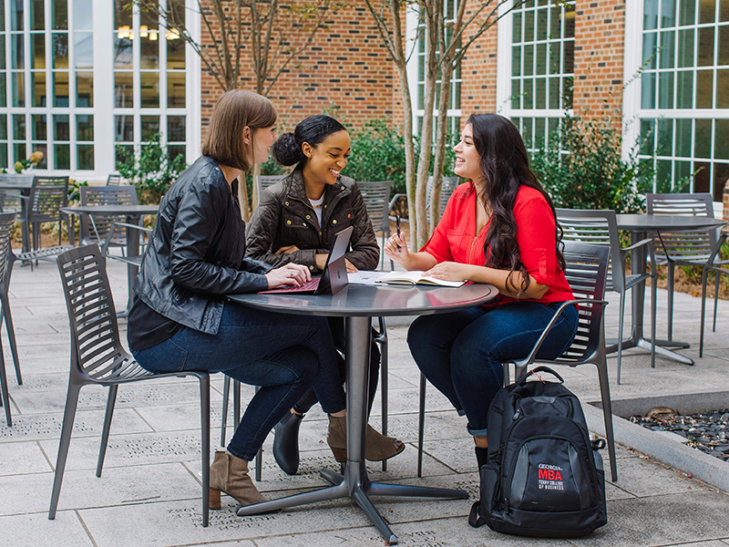 Professional women talking at a table outside.