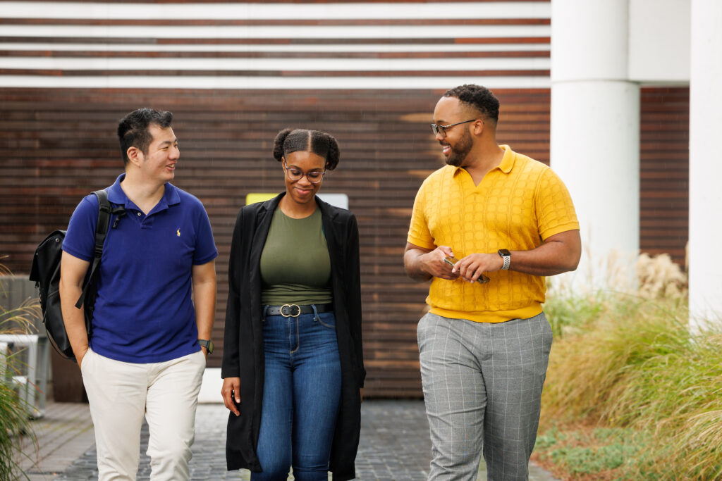 Three MPAcc students walking outside and chatting with each other