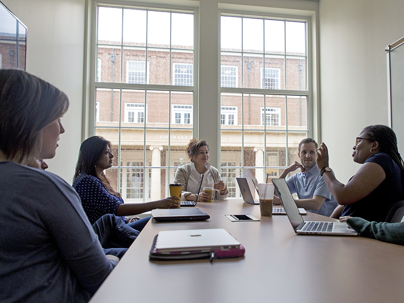 Management professor Marie Mitchell (center) speaks with graduate students.