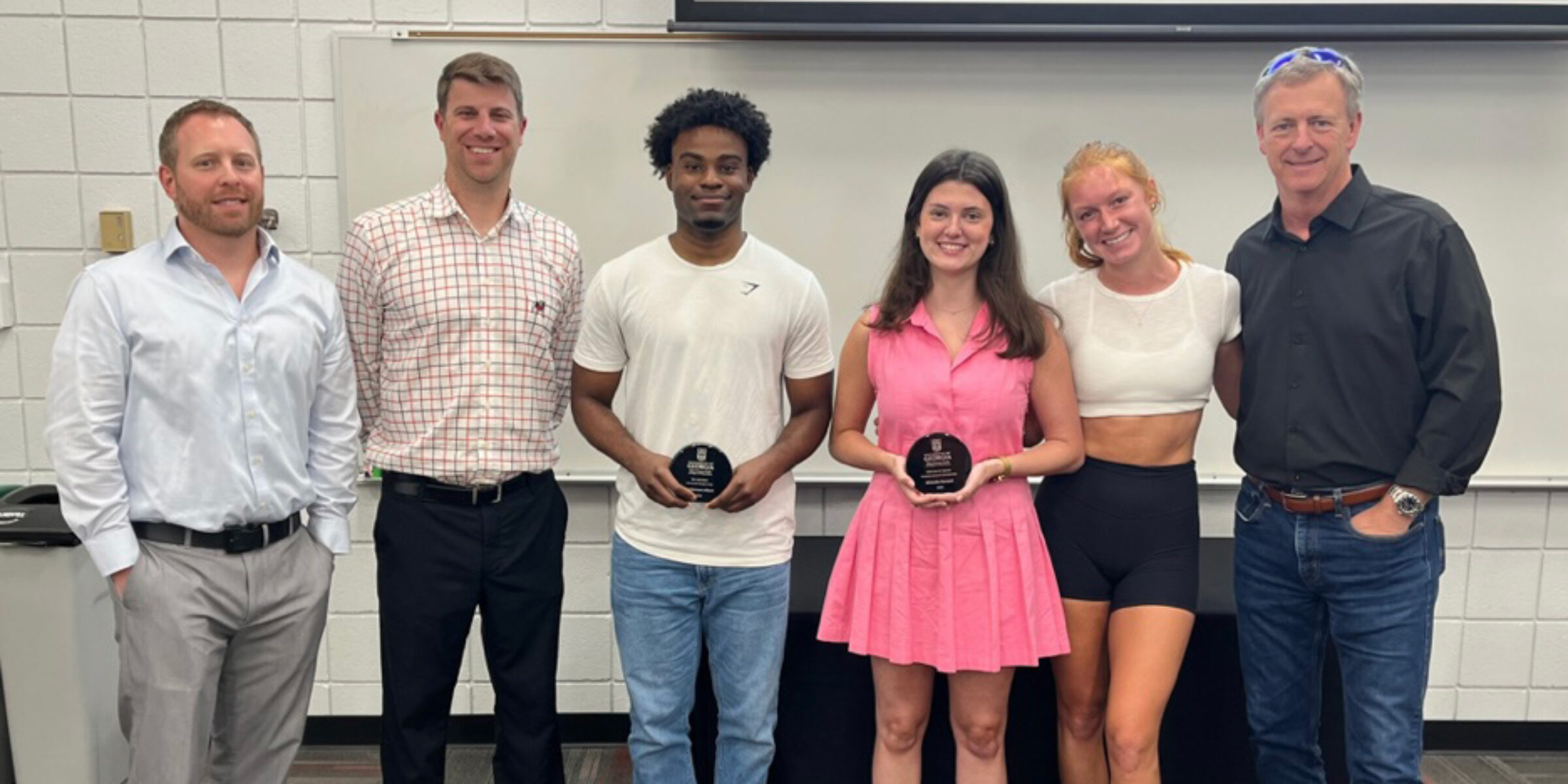 Sport management professors Steven Salaga, Mike Slonaker, far left, and Michael Cheney, far right, congratulate three students on receiving sports management scholarships.