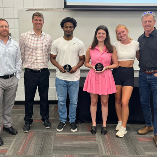 Sport management professors Steven Salaga, Mike Slonaker, far left, and Michael Cheney, far right, congratulate three students on receiving sports management scholarships.