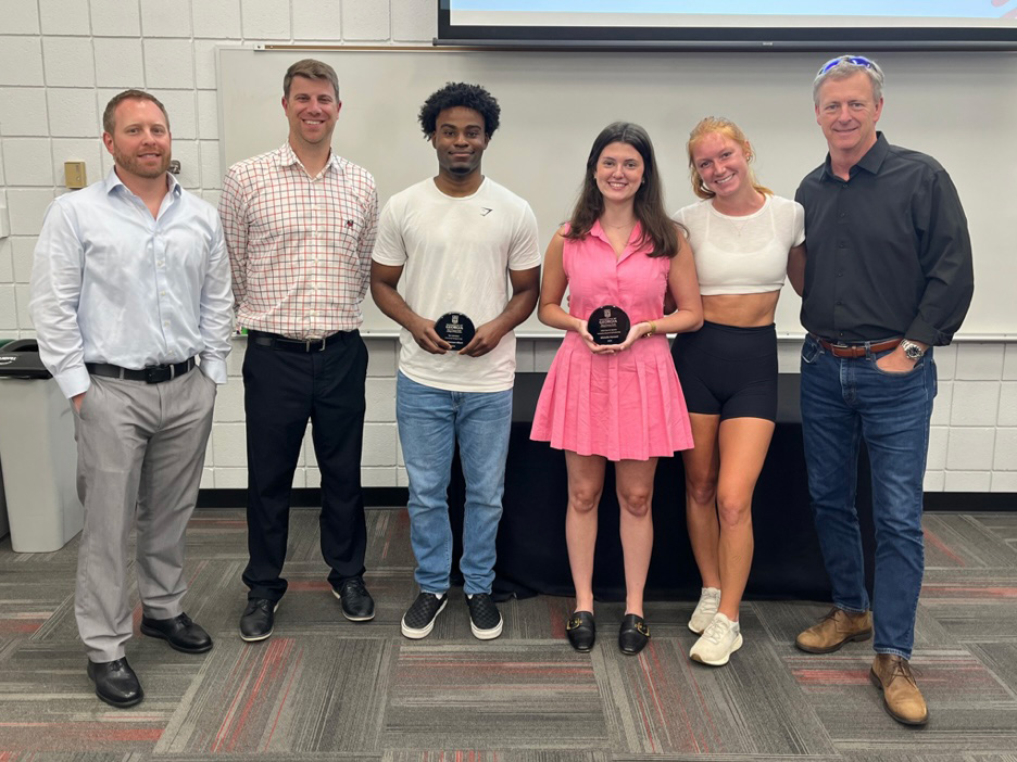 Sport management professors Steven Salaga, Mike Slonaker, far left, and Michael Cheney, far right, congratulate three students on receiving sports management scholarships.