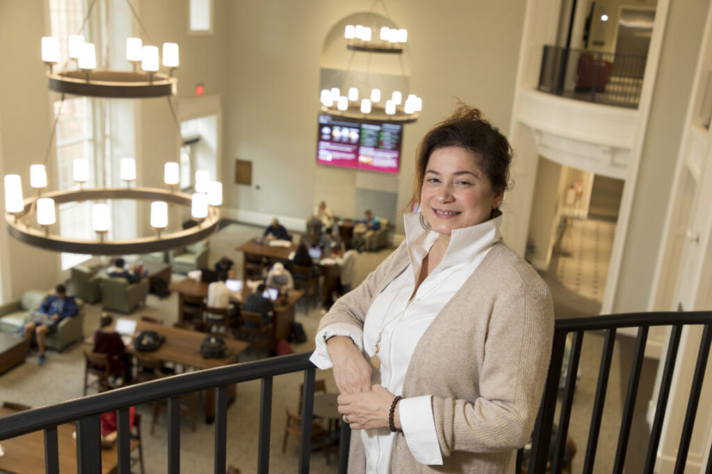 Associate professor Marie Mitchell stands along the railing above the Casey Commons inside Amos Hall in the Terry College Business Learning Community.