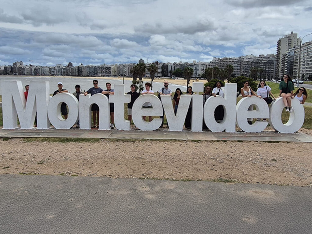 Students pose with the Montevideo sign in the capital of Uruguay during a winter study away trip.