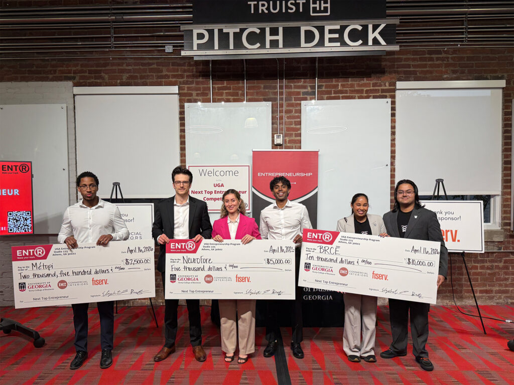 NTE2026winners Young entrepreneurs stand below a Truist Pitch Deck Sign at Studio 225 hold novelty large prize checks.