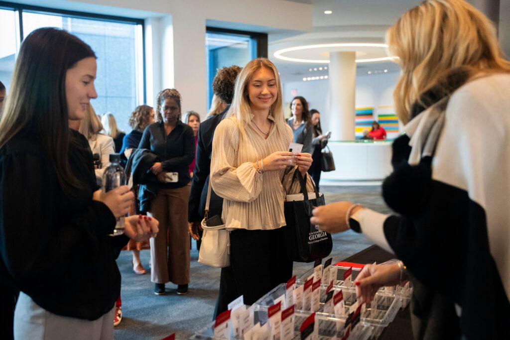 Two young women pick up their name tags from registration at the Terry College Professional Women's Conference.