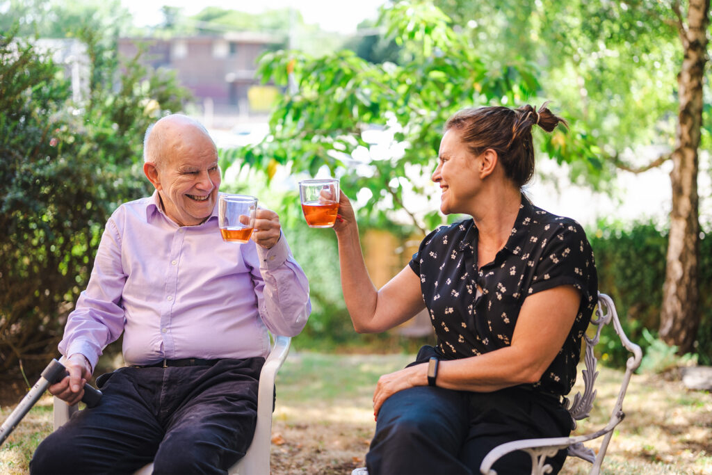 Older man drinking tea outside with his daughter