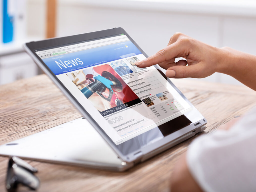 A hand taps on online ad on a news website displayed on a tablet.