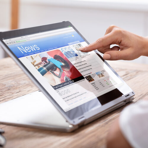 A hand taps on online ad on a news website displayed on a tablet.