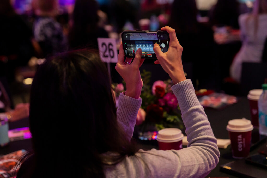 Close up of a woman's phone as she takes a photo of a slide at the Terry College Professional Women's Conference. The slide is describing EY's POWER Up Program. 