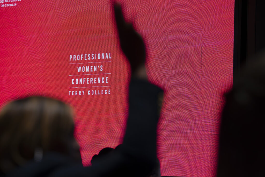Professional Womens Conference Title Slide with someone raising their hand in front of it .