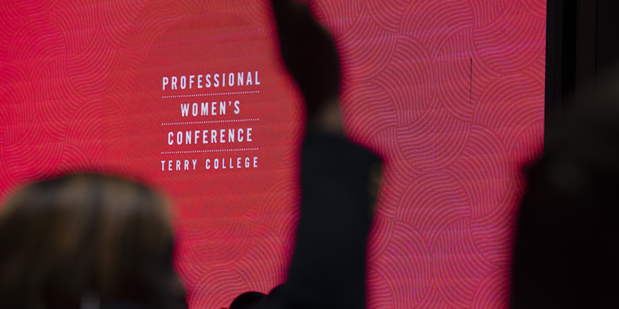 Professional Womens Conference Title Slide with someone raising their hand in front of it .