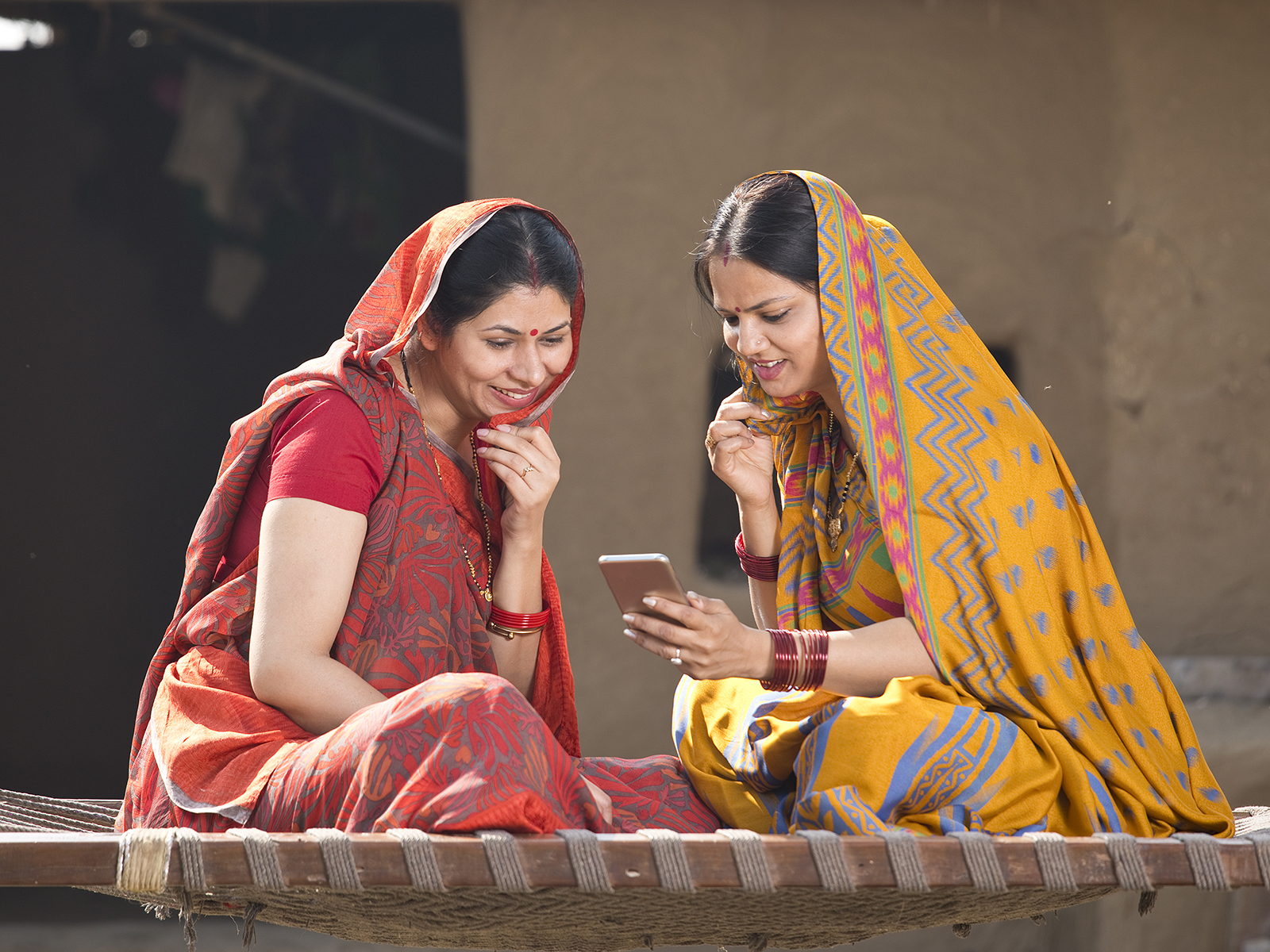 A female peer health educator in rural India shows another women a video message supporting cervical cancer screening. -Peer Health Educators