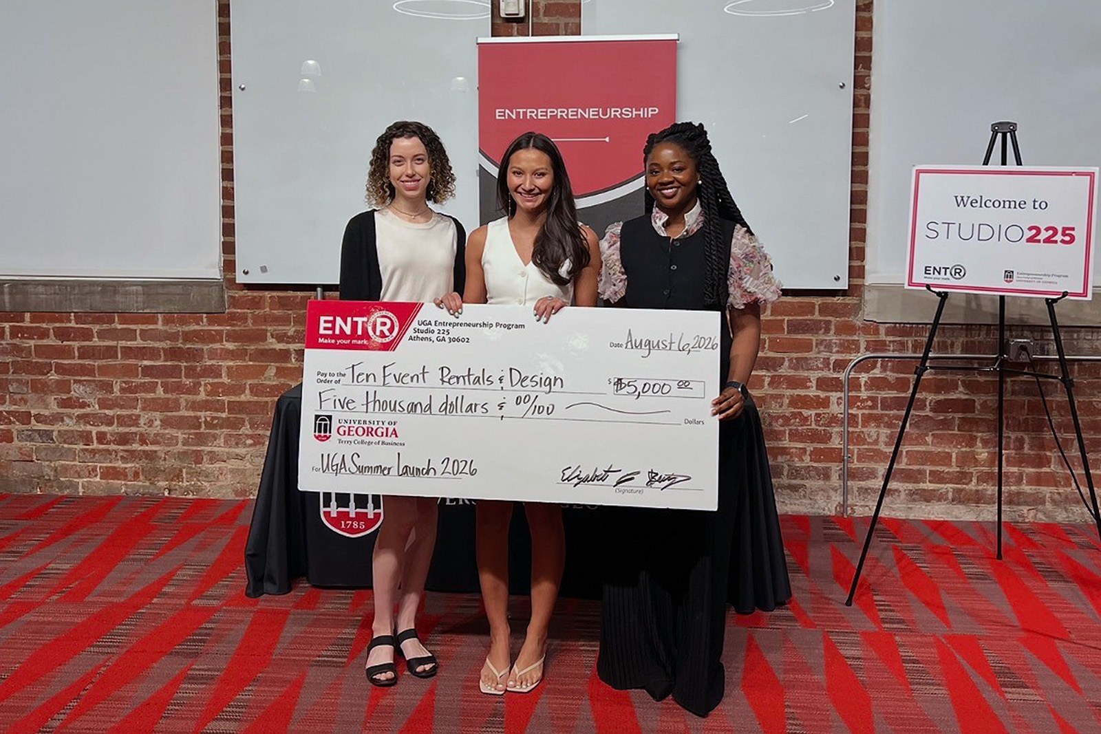 Moren Wallon, far left, and Jane Odum, far right, pose with Tenley Pelissier who holds a novelty prize check for $5000