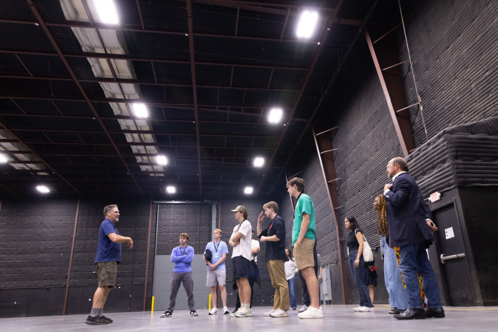 Students stand in crowd in the middle of a giant, empty sound stage