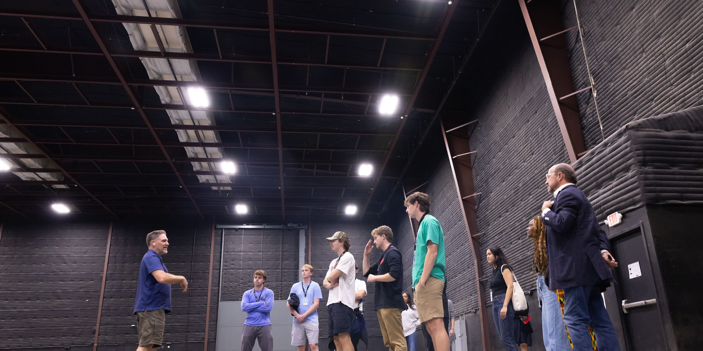 Students stand in crowd in the middle of a giant, empty sound stage