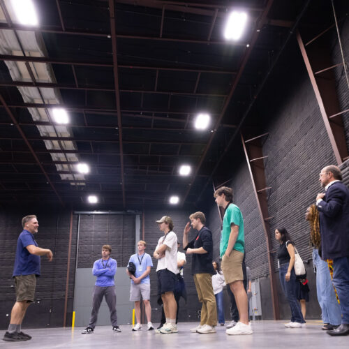 Students stand in crowd in the middle of a giant, empty sound stage