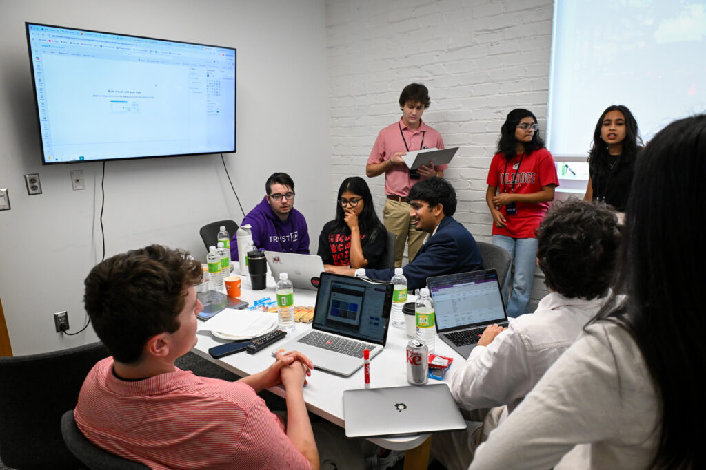 Truis_EXP_Workroom Students huddle in work room with IT experts from Truist during a immersive learning experience created and hosted by Truist.