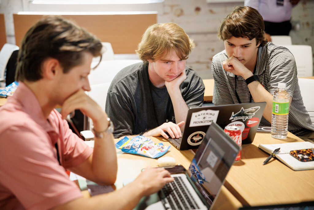 Students work on their computers, huddled around at table during a immersive learning experience created and hosted by Truist. Students work on their computers, huddled around at table during a immersive learning experience created and hosted by Truist.