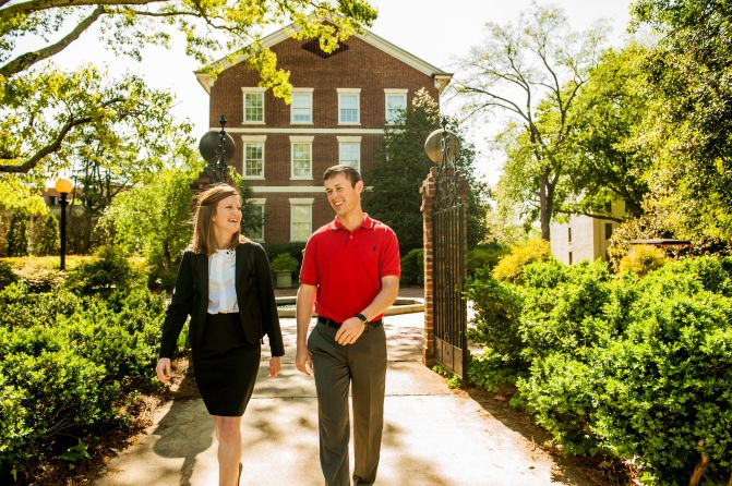 Two people walking and speaking outside a building