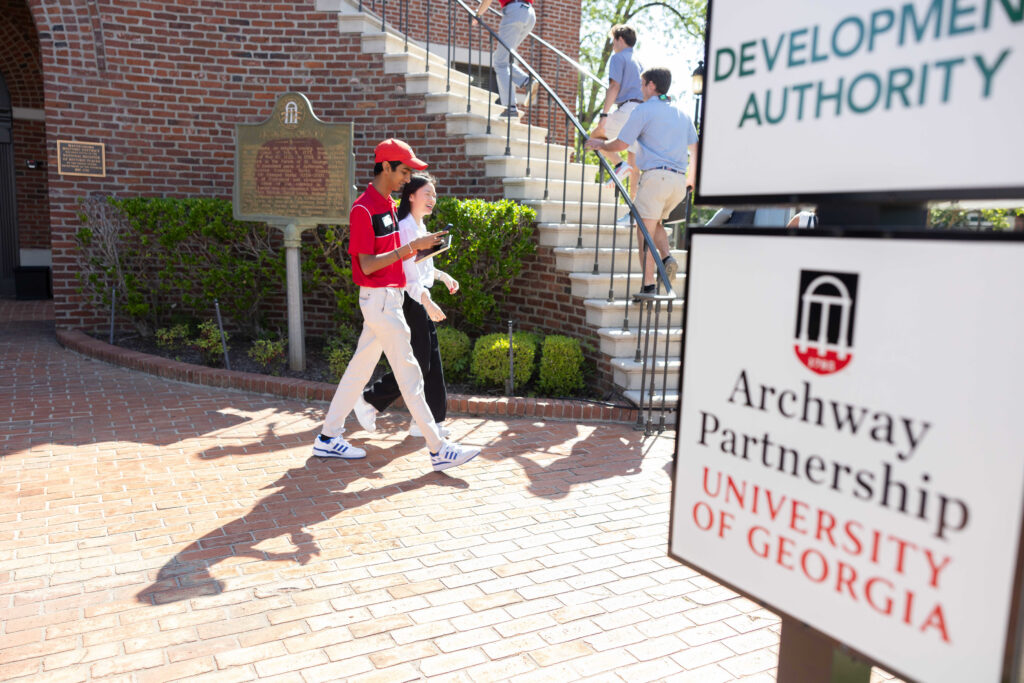 UGA students walk past an UGA Archway Partnership sign in downtown Waynesboro.