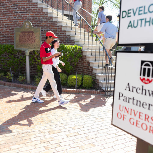 UGA students walk past an UGA Archway Partnership sign in downtown Waynesboro.