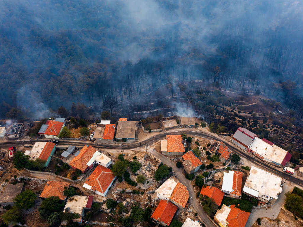 An aerial photo of a neighborhood being approached by wildfire