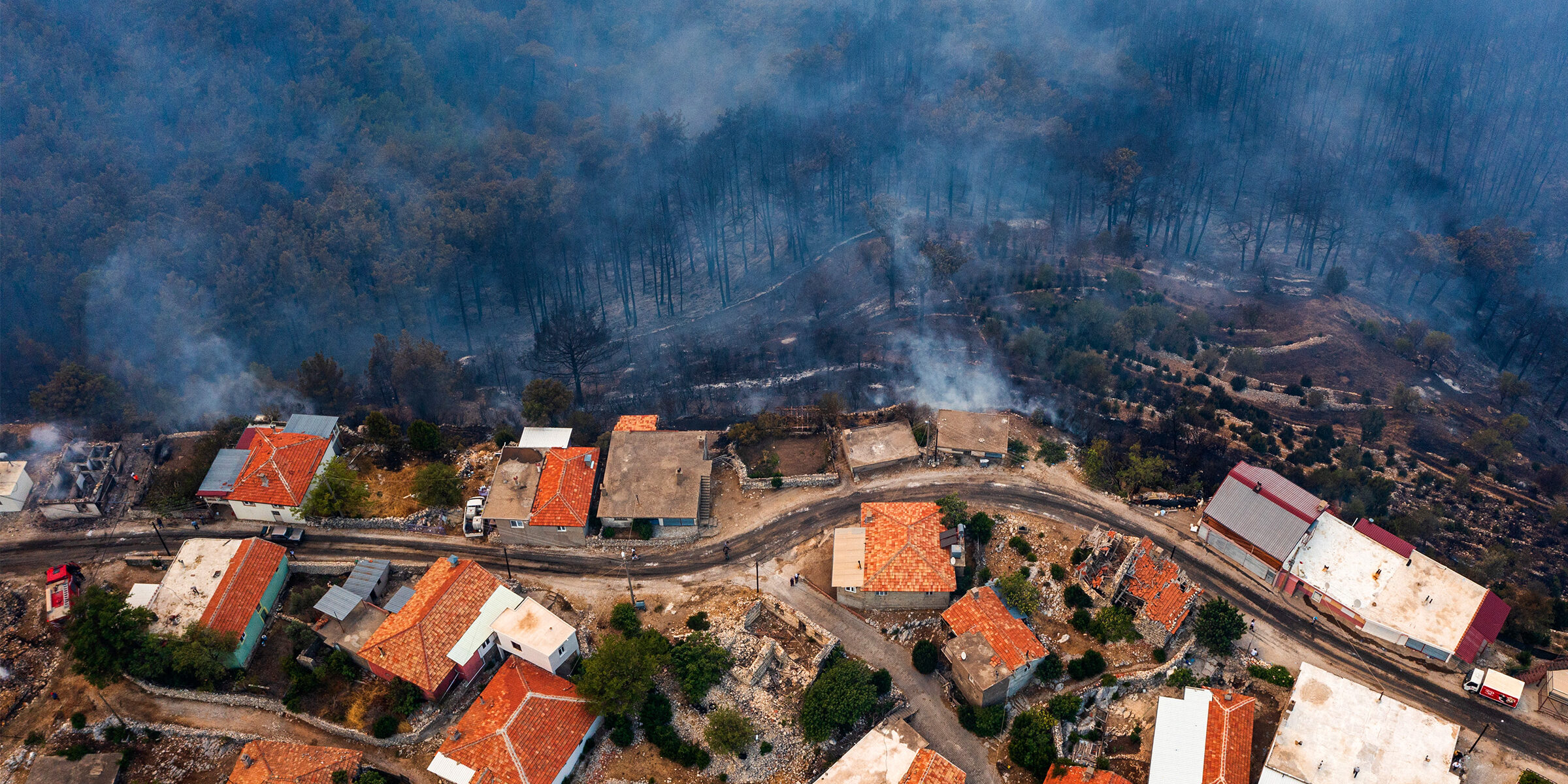 An aerial photo of a neighborhood being approached by wildfire