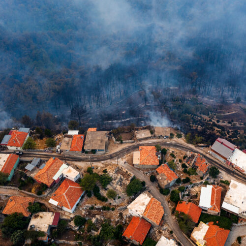 An aerial photo of a neighborhood being approached by wildfire