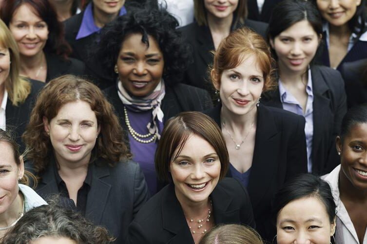 A diverse group of professional women dressed in business attire, engaged in a meeting or discussion.