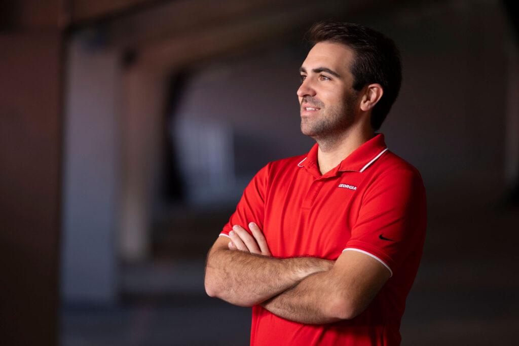 male student with Georgia branded polo with well let face against dark background