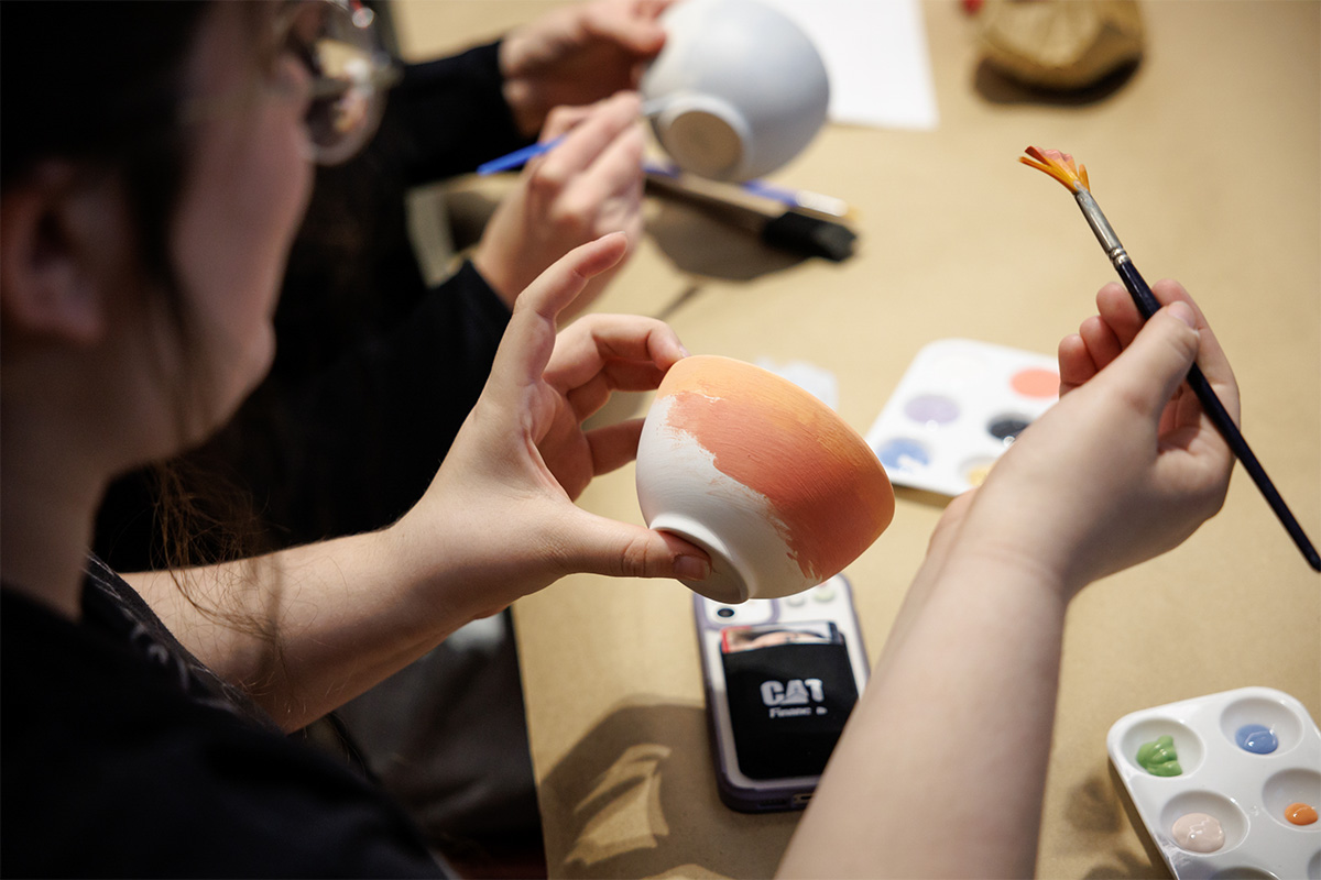 Closeup of ceramic bowl being painted orange