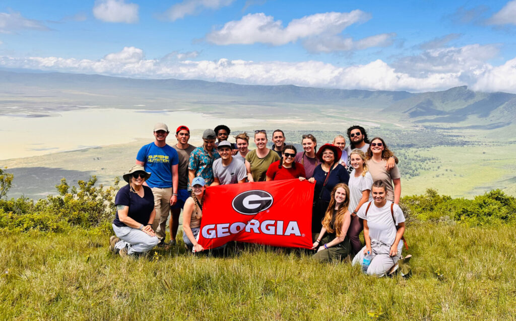 Students on a study abroad trip posing on a mountain ridge with UGA flag. Terry College is launching a project-based business study abroad program in Uruguay.