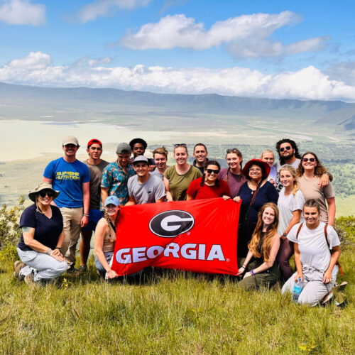 Students on a study abroad trip posing on a mountain ridge with UGA flag. Terry College is launching a project-based business study abroad program in Uruguay.