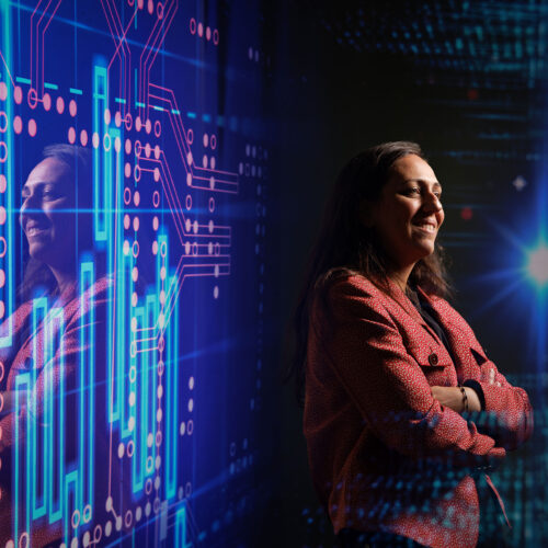 woman poses in dark room with abstract digital backdrop